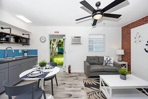 A modern kitchen with a dining area, a ceiling fan, and a view of the outdoors.