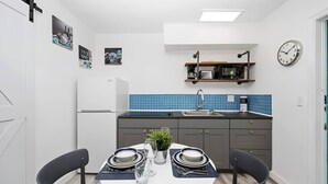 A compact kitchen with a white refrigerator, blue backsplash, and a clock on the wall. - Luna Beach House (Hollywood)