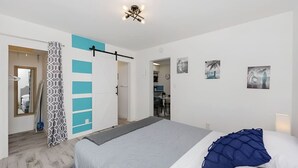 A modern bedroom with a bed, a wardrobe, a mirror, and a door leading to a bathroom. - Luna Beach House (Hollywood)
