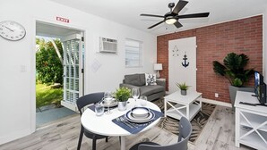A dining area with a round table, chairs, a ceiling fan, a brick wall, and a door marked 'EXIT'. - Luna Beach House (Hollywood)