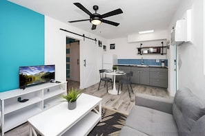 A modern living room with a TV, sofa, dining area, and kitchen. - Luna Beach House (Hollywood)