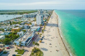 A coastal cityscape with a beachfront, high-rise buildings, and a marina.