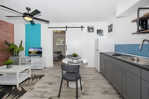 Uma cozinha compacta com área de refeições, ventilador de teto e televisão.