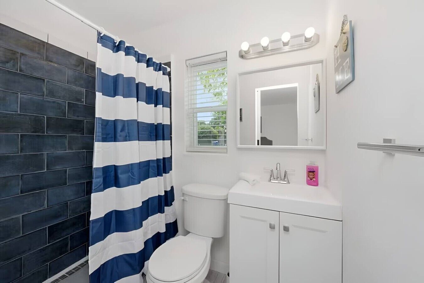 A bathroom with a white toilet, a sink with a mirror above it, and a shower curtain with a blue and white pattern.
