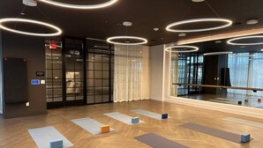 Un estudio de yoga moderno con suelos de madera, varias colchonetas de yoga y un espejo grande.