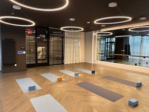 Ein modernes Yoga-Studio mit Holzböden, mehreren Yogamatten und einem großen Spiegel.
