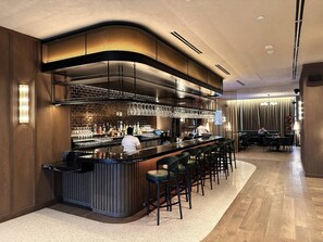 Eine moderne Bar mit einer gebogenen Theke, mehreren Hockern und einem Barkeeper.