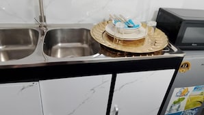 A kitchen with a double stainless steel sink, a microwave, and a dish rack with plates and utensils. - Duminy Guest Lodge (Duminy Street)