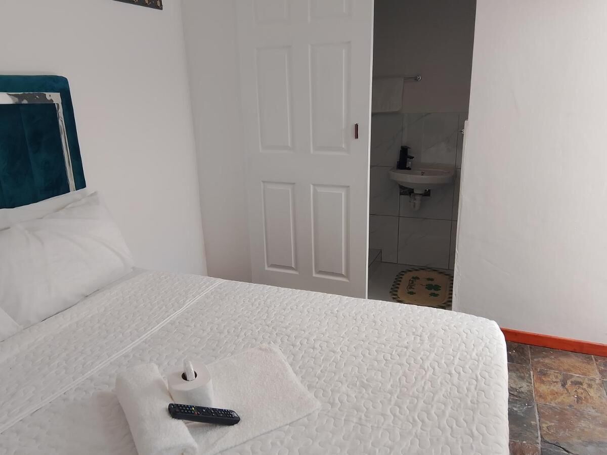 A hotel room with a bed, a remote control, and a towel on the bed.