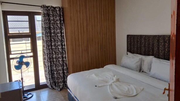 A hotel room with a bed, a fan, a curtain, and a wooden panel. - Duminy Guest Lodge (Duminy Street)