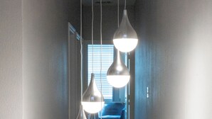 A hallway with hanging pendant lights and a carpeted floor.