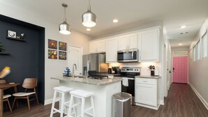 A modern kitchen with white cabinets, stainless steel appliances, and a central island with bar stools.
