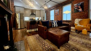 Un salon moderne avec un canapé en cuir marron, un tapis à motifs et un fauteuil jaune.