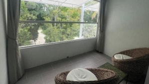 A balcony with a view of greenery and a river. There are two wicker chairs with cushions. - Charming Suite @Islamorada With Pool Access - Twilight Suite (Islamorada)