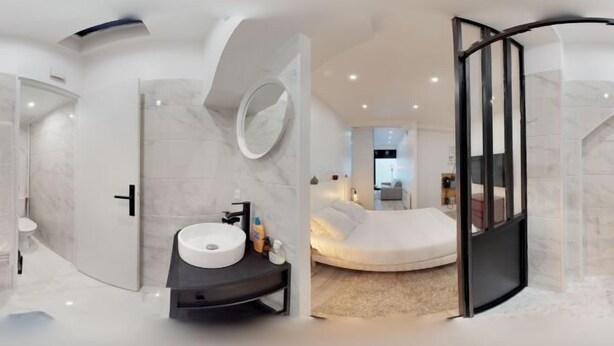 Un baño moderno con un diseño curvo, un espejo redondo y un lavamanos blanco.