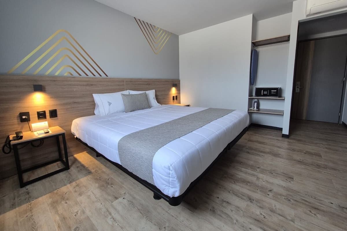 Habitación de hotel moderna con una cama grande, mesitas de noche, un armario y un equipo de aire acondicionado de pared.