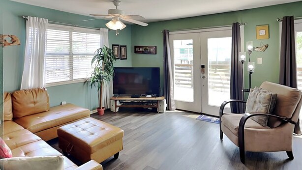 A living room with a sofa, a chair, a coffee table, a television, and a potted plant. - The Anchorage by Silver Sands Vacation Rentals (Port Aransas)