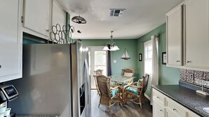 A kitchen with a refrigerator, dining table, chairs, and cabinets. - The Anchorage by Silver Sands Vacation Rentals (Port Aransas)