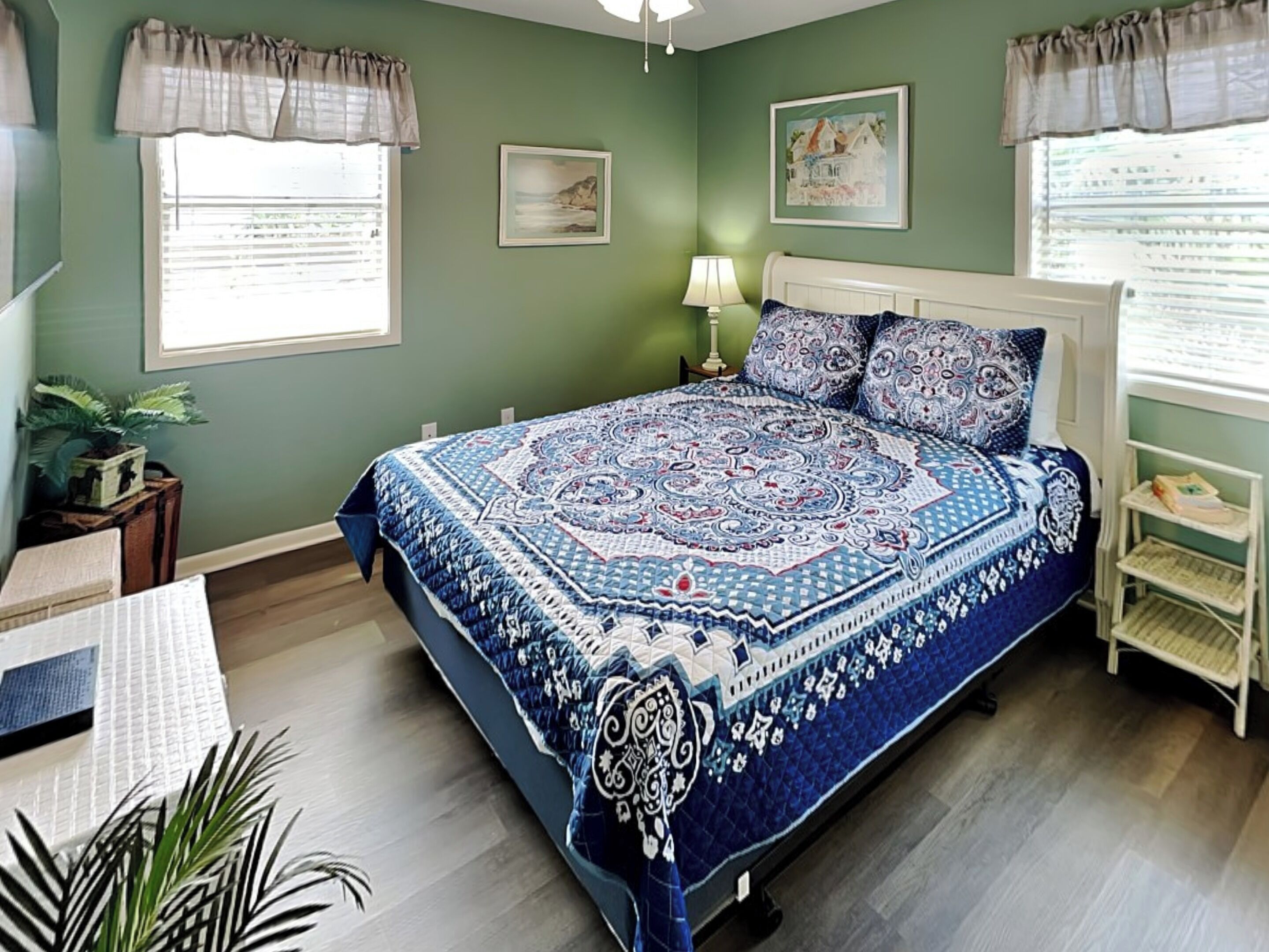 Un dormitorio con cama, mesita de noche, lámpara y ventana con cortinas.