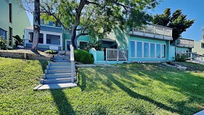 A two-story house with a front porch, a staircase leading to the entrance, and a well-maintained lawn. - Watercolor Skies by Silver Sands Vacation Rentals (Port Aransas)