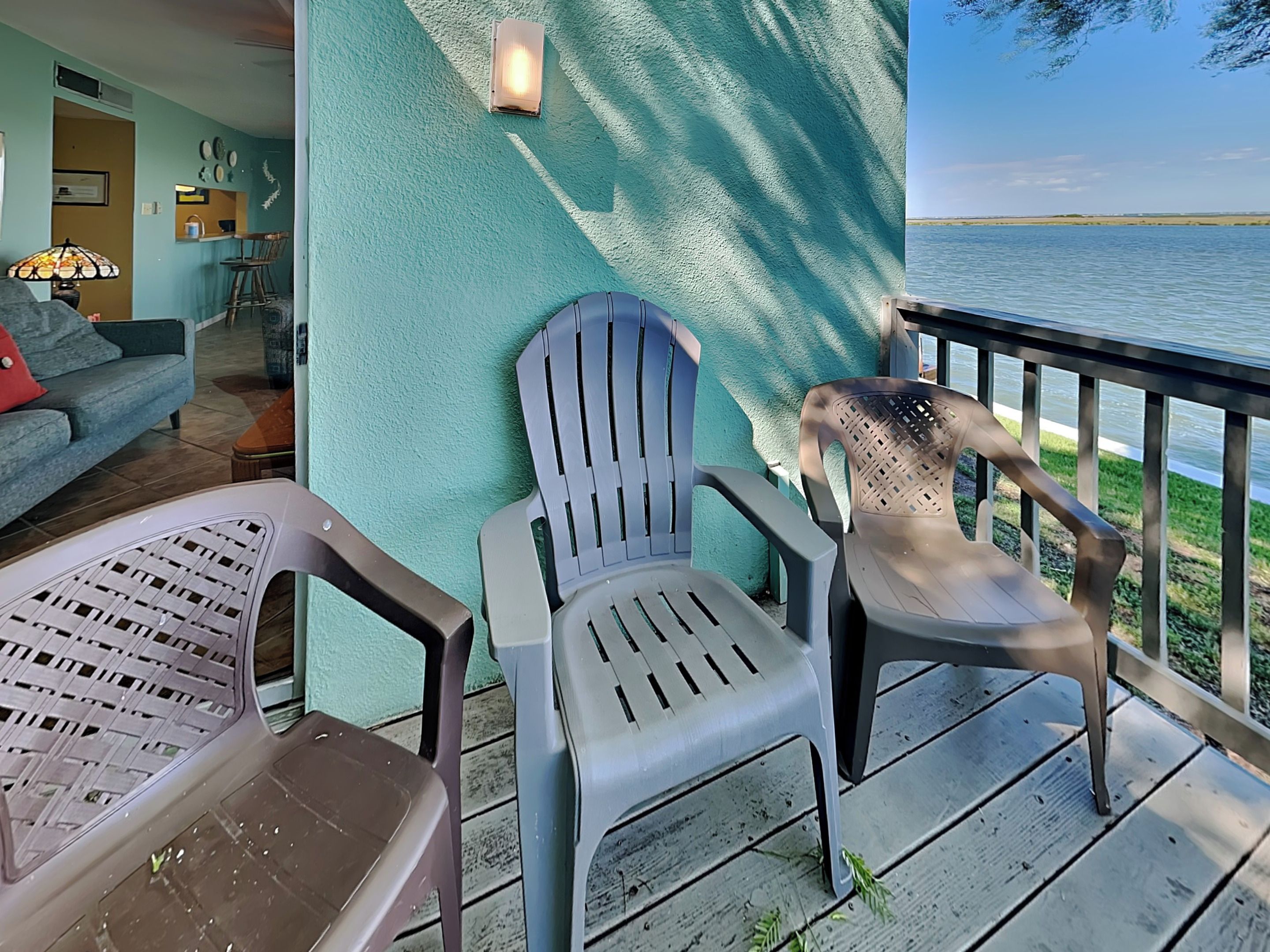 A deck with outdoor seating, a view of the water, and a teal wall.
