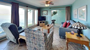 Ein Wohnzimmer mit Sofa, Sesseln, Couchtisch und Fernseher.