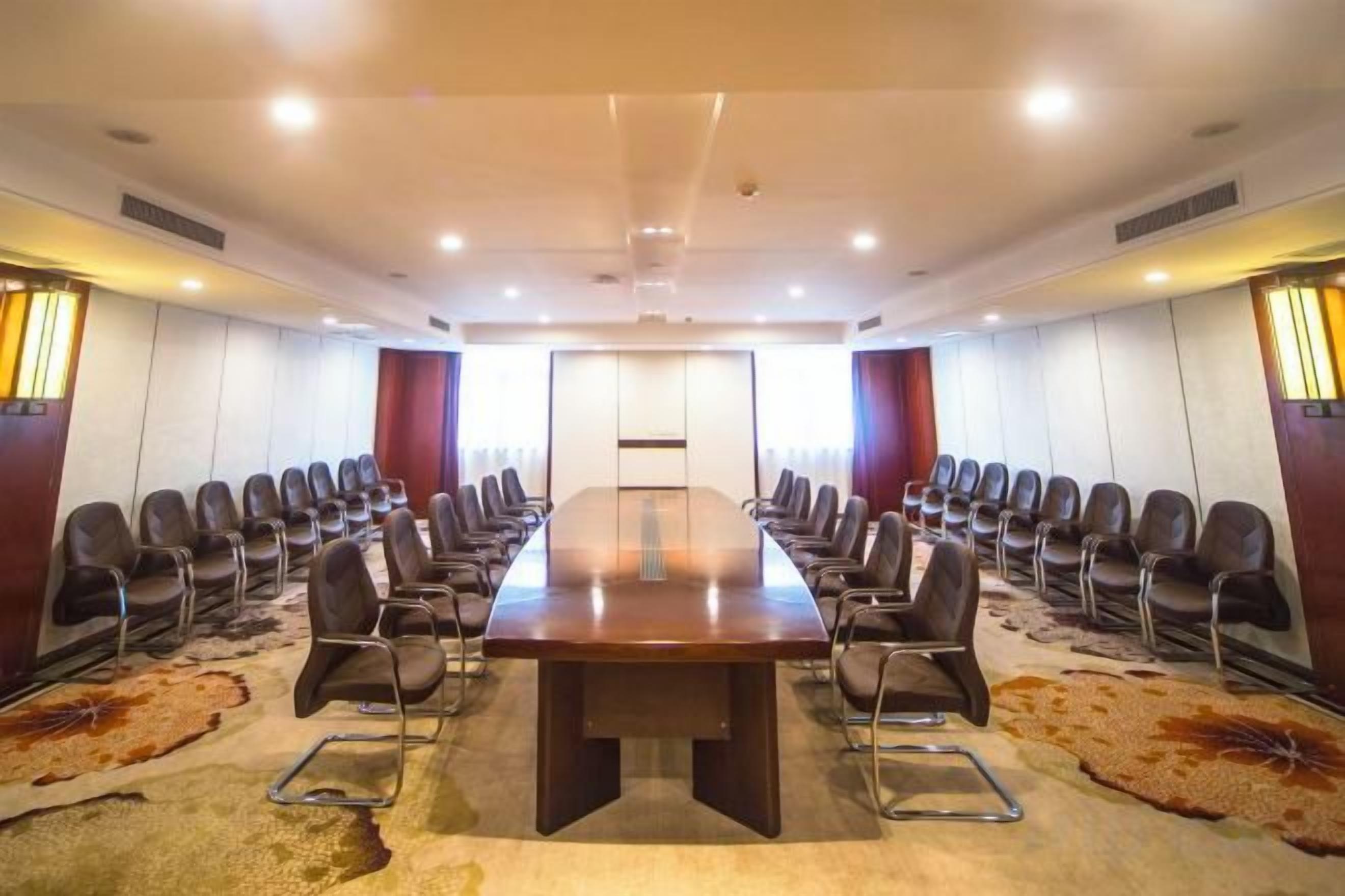 Un salón de conferencias con una larga mesa, sillas y suelo alfombrado.