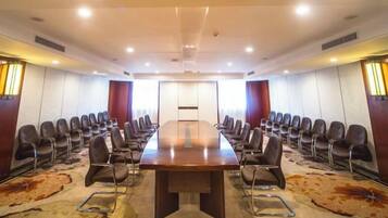 Un salón de conferencias con una larga mesa, sillas y suelo alfombrado.