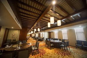 A hotel conference room with high ceilings, chandeliers, and a carpeted floor.