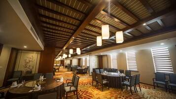 A hotel conference room with tables, chairs, and a patterned carpet.