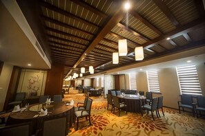 Un salón de conferencias de hotel con mesas, sillas y una alfombra estampada.
