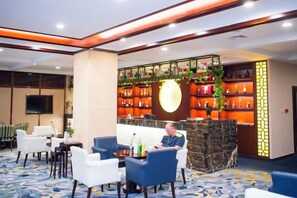 Un vestíbulo con mostrador de recepción, zona de estar y un bar con estantes llenos de botellas.