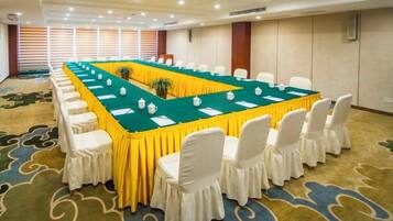 A conference room with a long table, white chairs, and a carpeted floor.