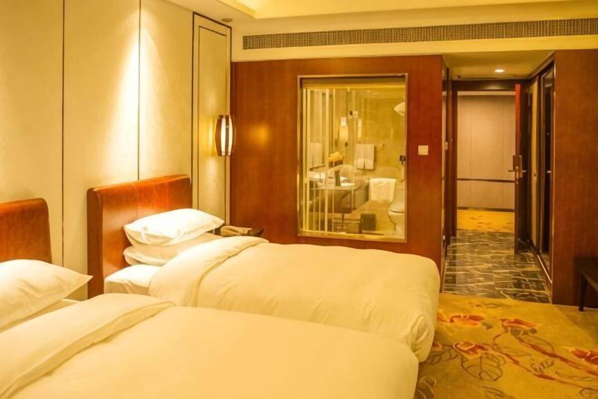A hotel room with two beds, a large mirror, and a view of the hallway.