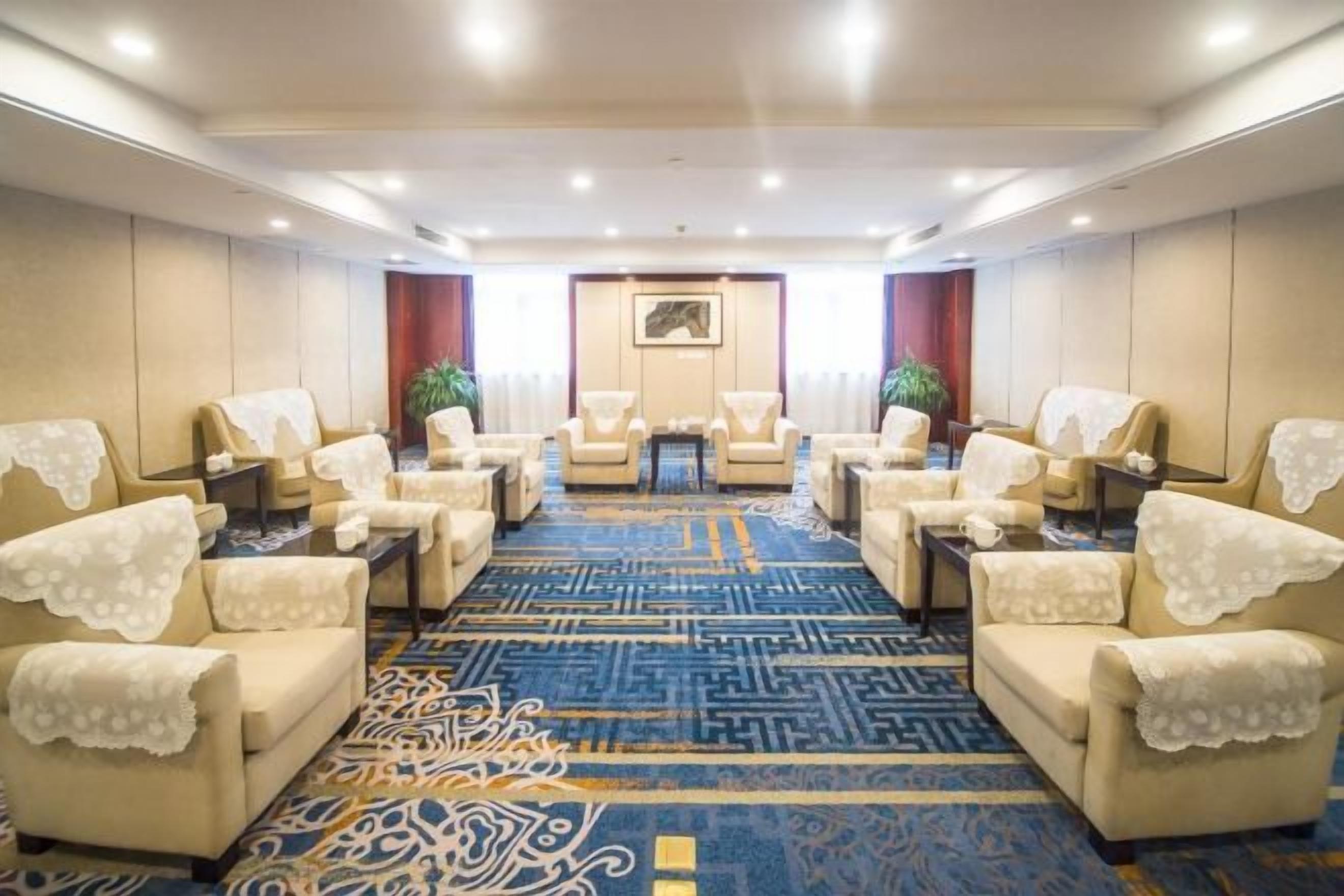 A conference room with a patterned carpet, multiple chairs, a table, and a framed picture on the wall.