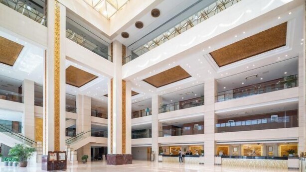 Ein mehrgeschossiges Atrium mit einer zentralen Säule, Glastrennvorrichtungen und einem Empfangsbereich.