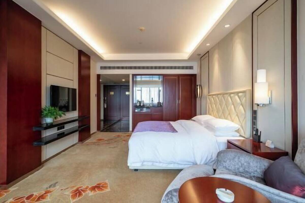 A hotel room with a bed, a sofa, a TV, and a desk.