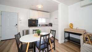Una cocina compacta con armarios blancos, un microondas negro y una mesa de comedor con sillas.