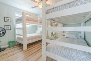 A bunk bed room with a ceiling fan, a small table with a lamp, and a framed picture on the wall. - Charming updated Surfside home with firepit - only 2 min walk to the beach! (Surfside Beach)