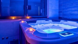 A modern spa room with a hot tub, a glass door leading outside, and a control panel on the hot tub. - Holiday Home Mali Raj (Josipdol)