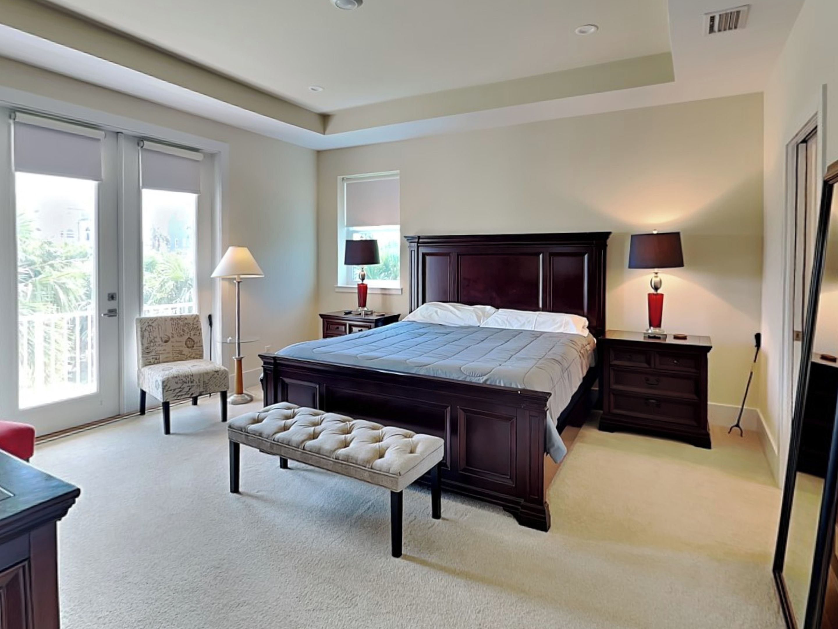 Une chambre à coucher avec un grand lit, un banc, une chaise, une table de chevet et une commode.