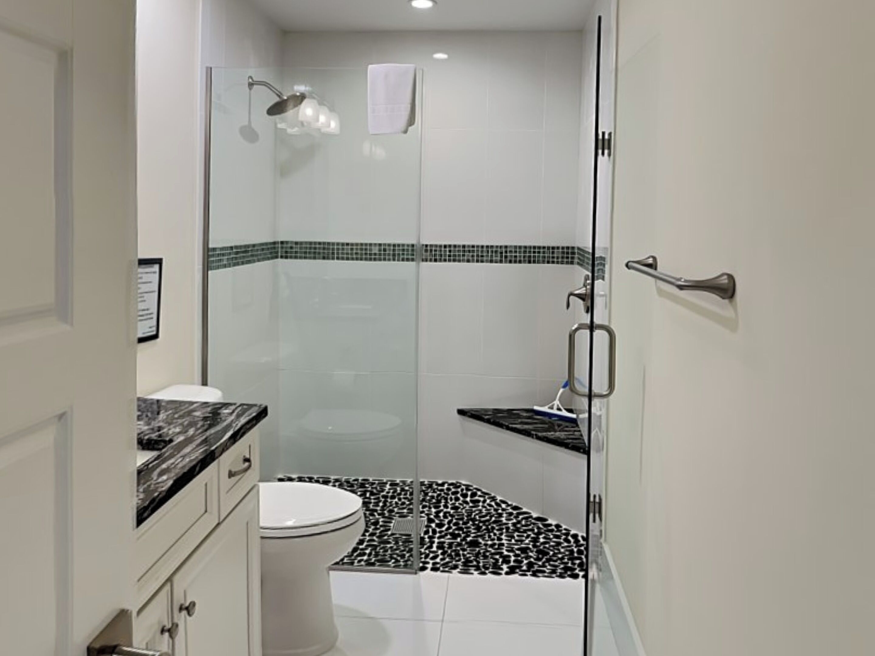 Une salle de bain moderne dotée d’une douche à parois de verre, de toilettes et d’un meuble-lavabo avec un plan de travail en marbre.