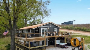 A two-story house with a deck, outdoor seating, and a hot tub. - The Breakaway at Table Rock- Sauna, Hot Tub, Kayak, Full Upper and Lower Porches (Omaha)