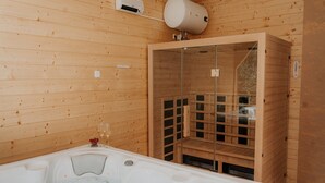 Egy faház, melyhez jakuzzi, szauna és üvegfalakkal körbevett zuhanyzó tartozik.
