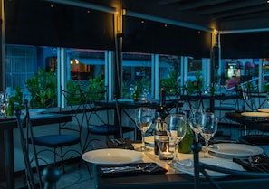 A restaurant setting with tables set for dining, wine glasses, and bottles, with a view of the outside. - Casa Condado Hotel & Residences 3Bed/4Bath Apt. (San Juan)