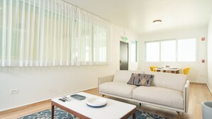 A modern living room with a sofa, a coffee table, and a dining table with chairs. - Casa Condado Hotel & Residences 3Bed/4Bath Apt. (San Juan)