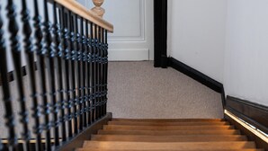 A wooden staircase with a black metal railing leading to a white door. - Apartment in Koblenz Near Deutsches Eck (Koblenz)
