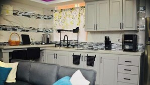 A modern kitchen with grey cabinets, a black coffee machine, and a tiled backsplash. - Ideal Studio Apartment,  AC, WIFI & parking, minutes from Stadium and the city (Mount Gay)