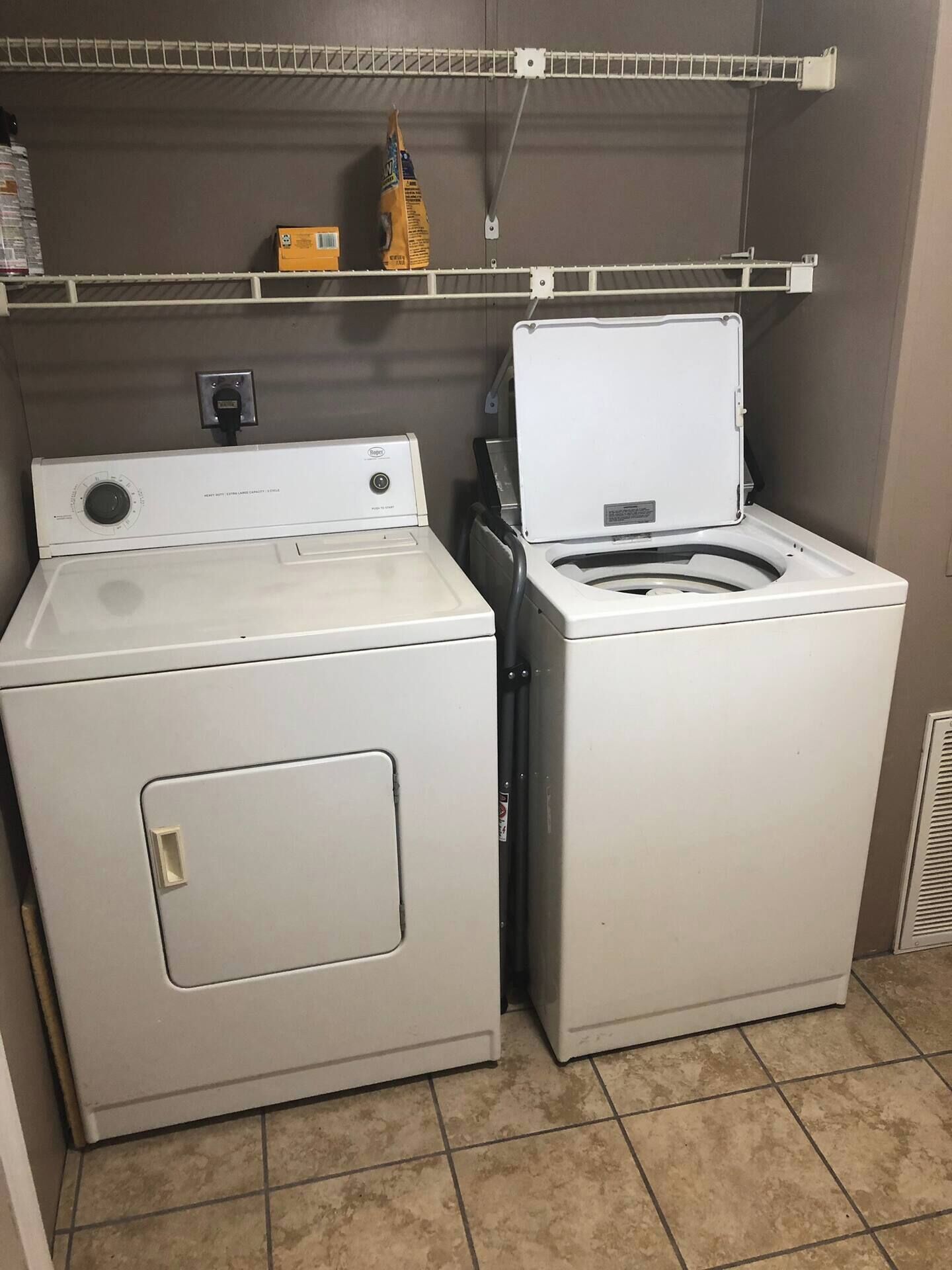 A laundry room with two stacked washers and dryers, a shelf above, and a tiled floor.
