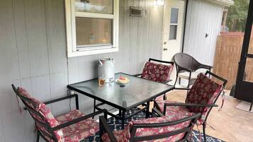 Un patio techado con una mesa y sillas, un farol de metal y una puerta que da a un espacio al aire libre.